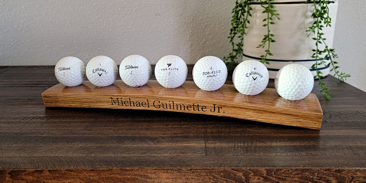 Golf balls displayed on a curved wooden stand engraved with a customer’s name