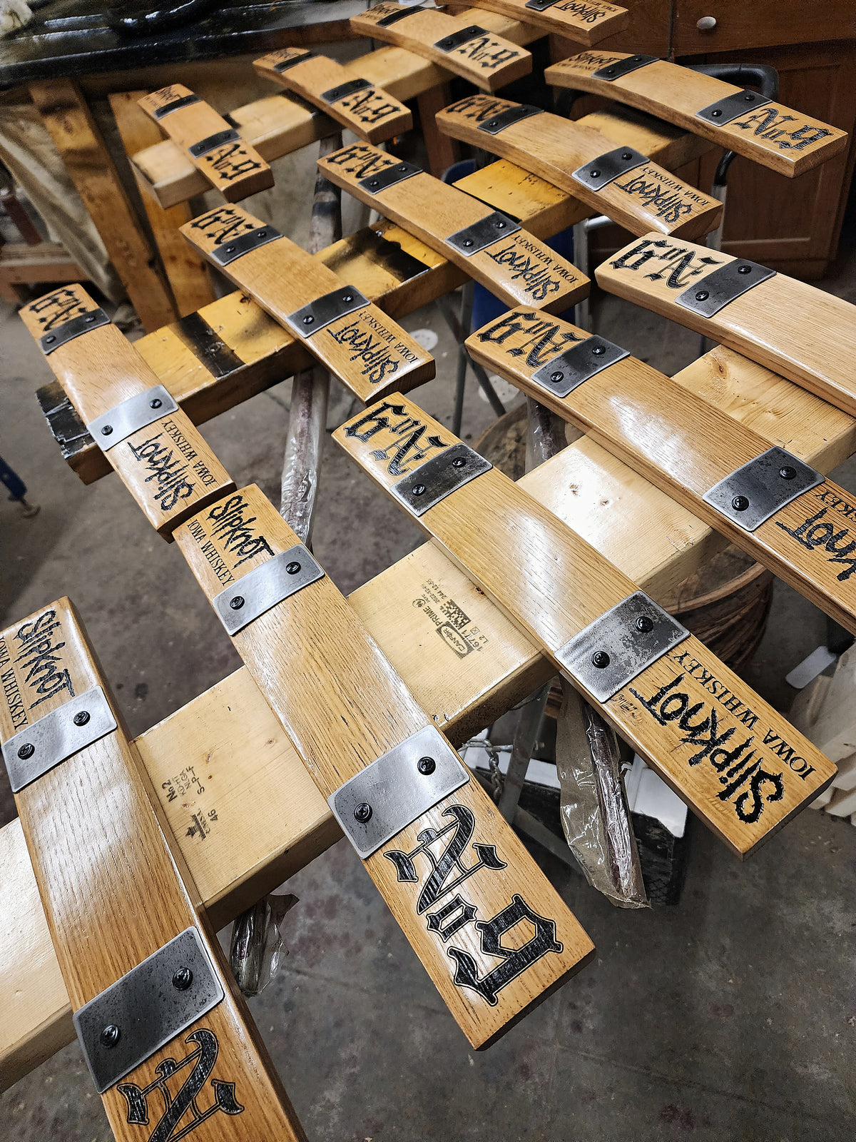Custom branded barrel stave pieces with metal hardware arranged in the workshop