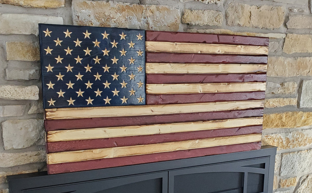 Handcrafted wooden American flag displayed against a stone fireplace