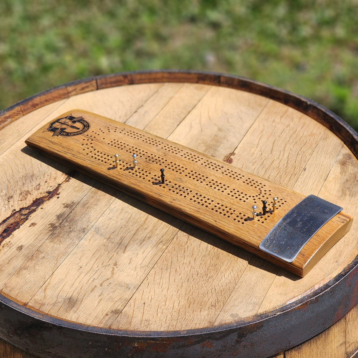 Engraved whiskey barrel stave cribbage board on a barrel head