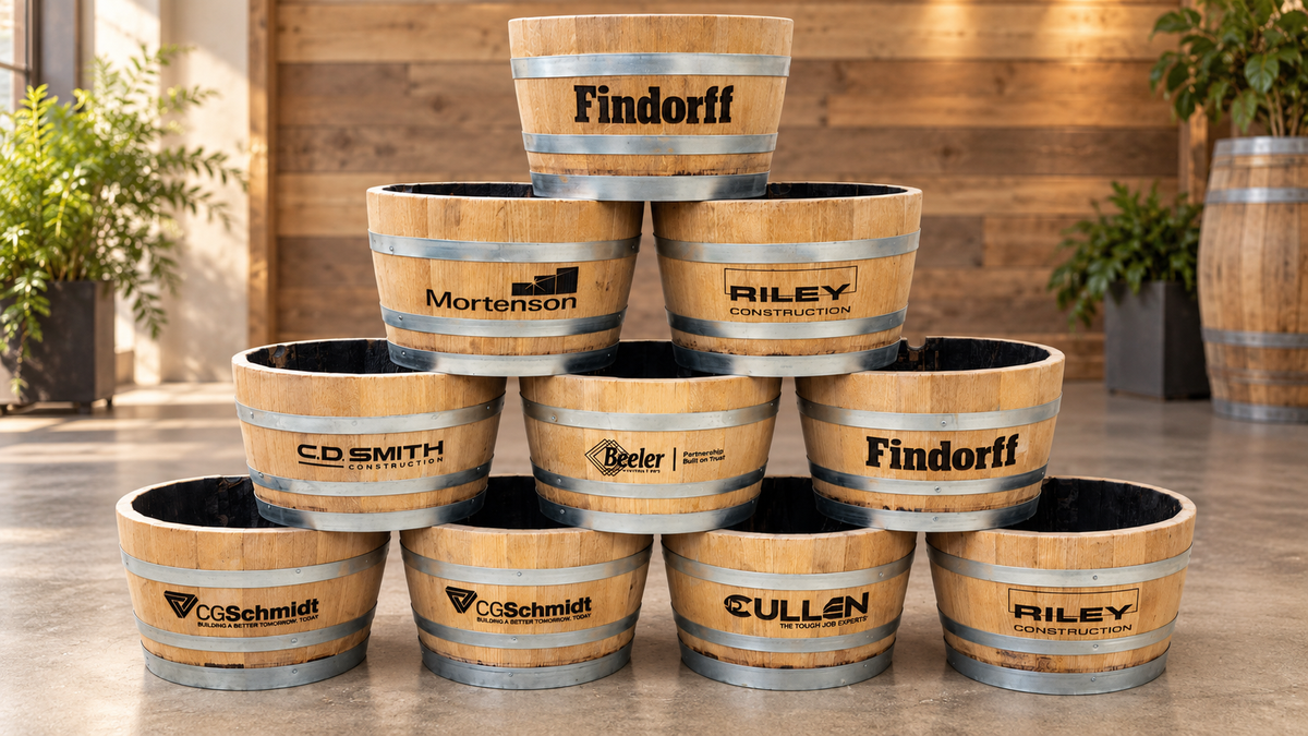 Custom whiskey barrel planters branded with company logos for a corporate order