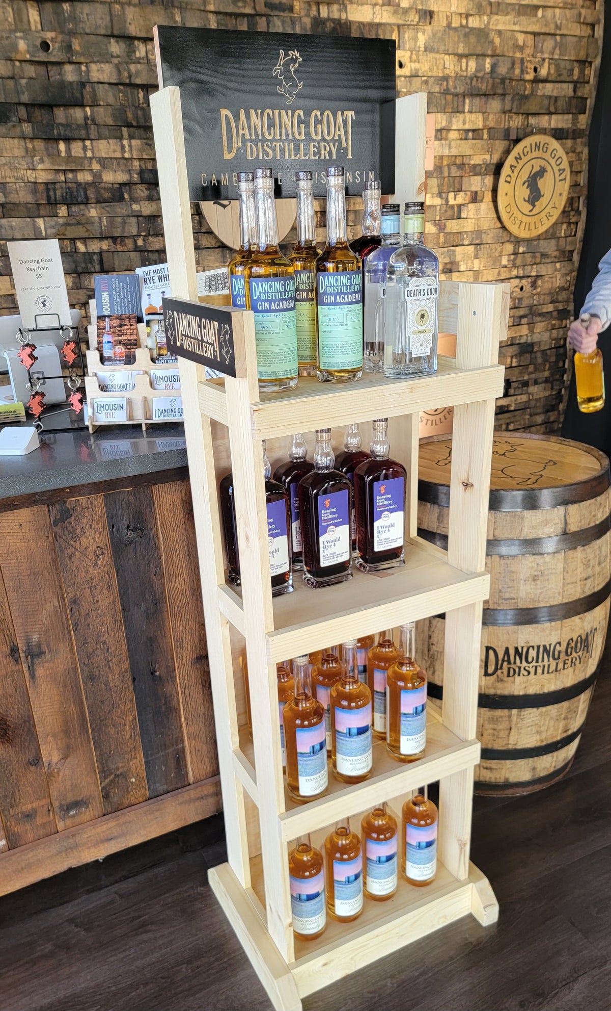 Dancing Goat Distillery wooden product display holding bottles on branded shelves in a tasting room