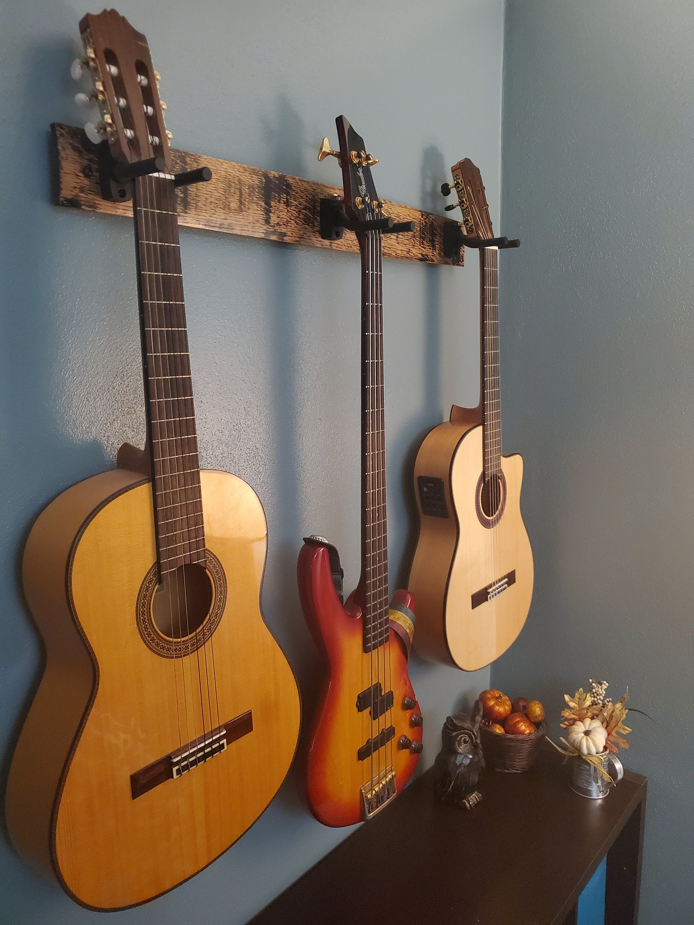 Three guitars displayed on a whiskey barrel stave wall mount