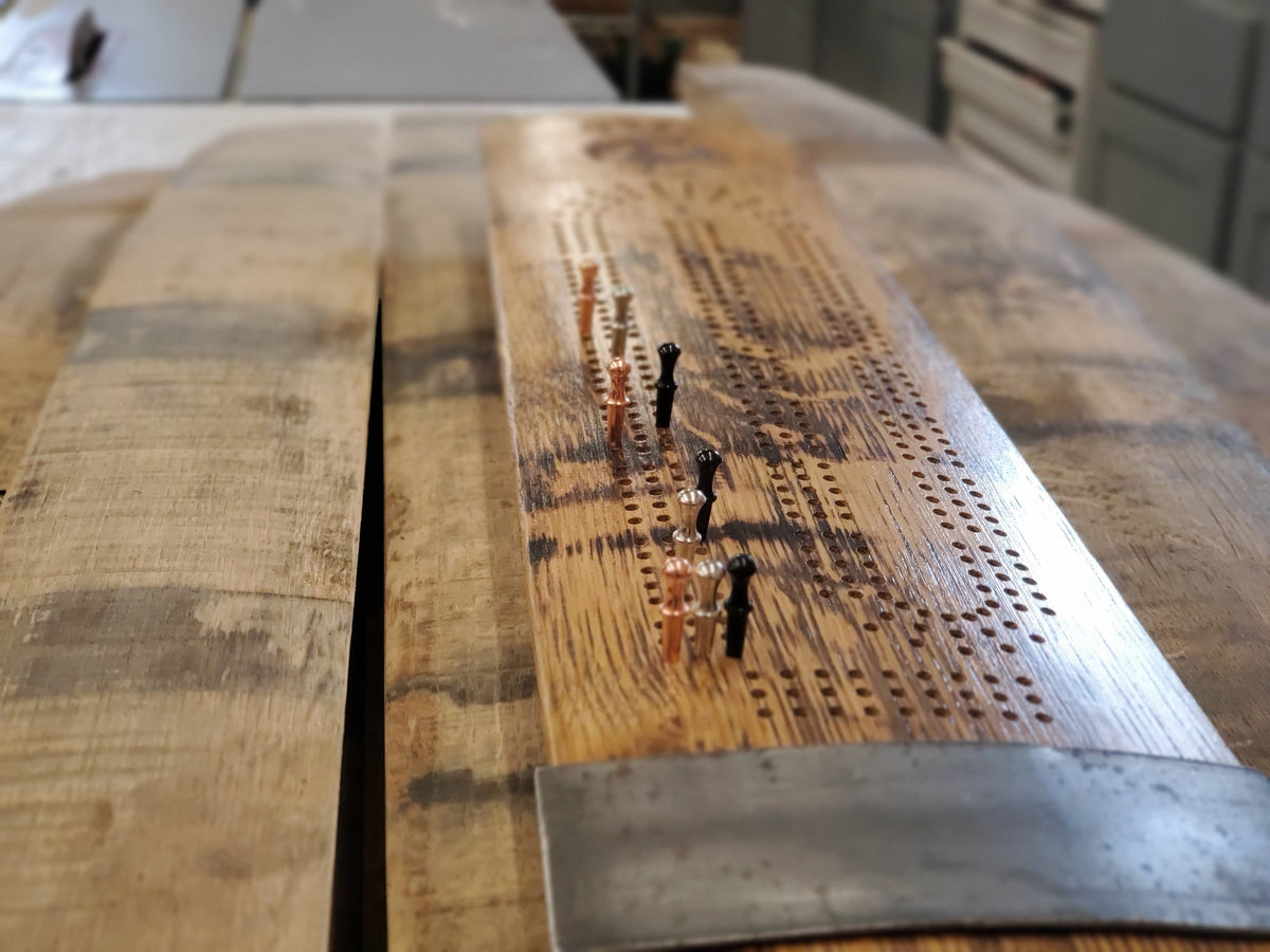 Reclaimed barrel stave cribbage board with metal end bands and playing pegs